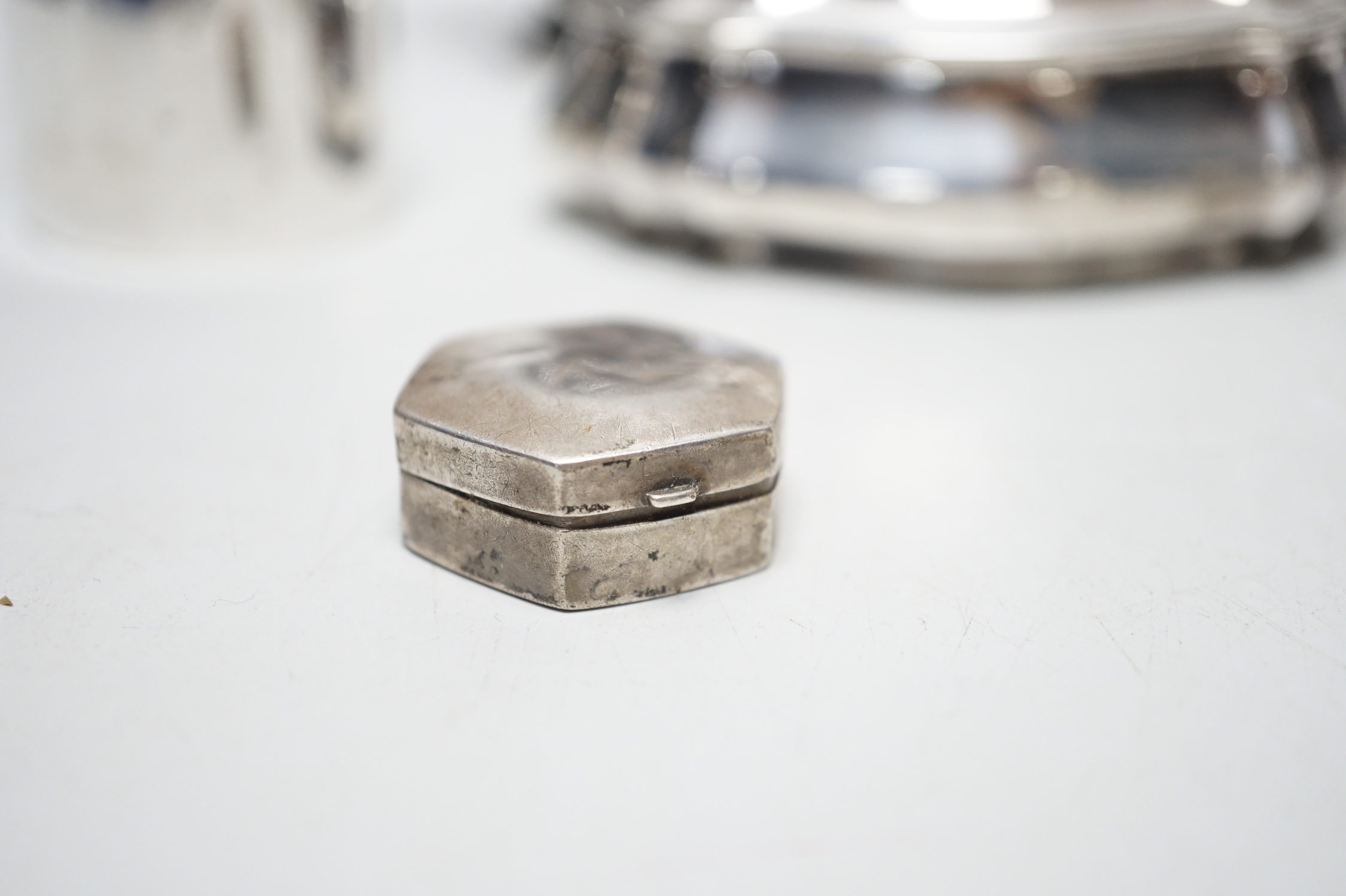 A late Victorian shaped oval silver trinket box, Birmingham, 1898, 99mm, a hexagonal silver pill box, a pair of silver toast racks and four silver serviette rings, a silver domed topped inkwell and a miniature silver two